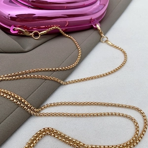 Detailed close-up of metallic rose pink clutch with polished gold box chain strap