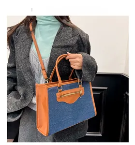 Detalle del bolso tote de mezclilla azul y cuero marrón con bolsillo con cremallera