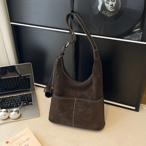 Large brown suede tote bag with contrast stitching and adjustable strap on a desk