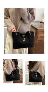 Detail of black suede tote bag with golden deer pendant and chain strap worn by a model