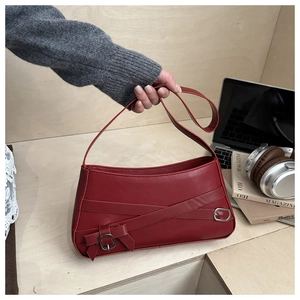 Detail of red faux leather shoulder bag with buckle strap and bow decoration