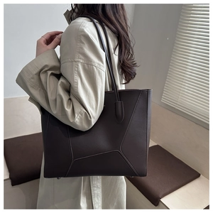 Détail du sac cabas marron foncé montrant les coutures géométriques et le logo en métal