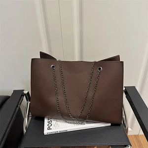 Grand sac cabas marron en cuir texturé avec bandoulière chaîne sur une chaise chic