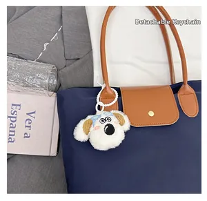Detachable white plush puppy pendant with blue bow on a navy nylon tote bag detail
