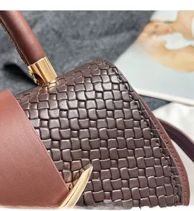 Detail shot of hand-woven dark brown leather checkered texture with smooth trim on handbag