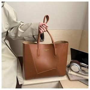 Détail du grand sac cabas marron avec coutures géométriques et logo doré brillant