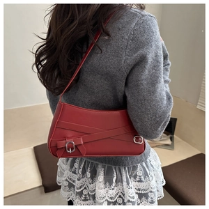 Detail of red leather shoulder bag with cross strap and silver buckle accent