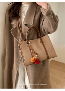 Dettaglio di una grande borsa tote in tessuto con finiture in pelle marrone e nappa