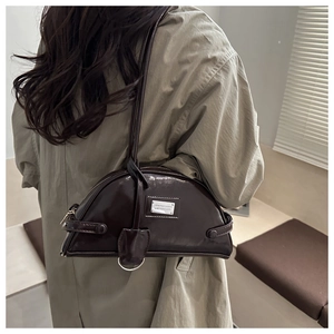 Close-up of a dark brown half-moon shoulder bag with glossy oil-wax leather and silver hardware
