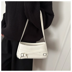 Close-up of white leather crescent bag with silver buckles and a sweet bow detail