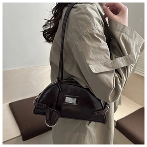 Detailed side view of a dark brown half-moon shoulder bag with shiny PU leather finish
