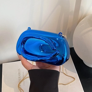 Detail of glossy electric blue clutch bag with fluid sculpted design and gold chain