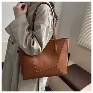 Gros plan sur le sac fourre-tout en cuir PU marron avec texture fine et lettrage doré