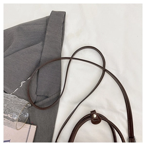 Detail of brown leather handbag with metallic rivets paired with a grey textured blazer