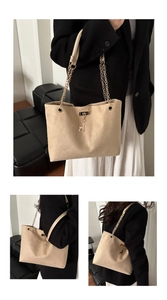 Close-up of beige suede tote bag featuring a gold deer charm and chain shoulder strap