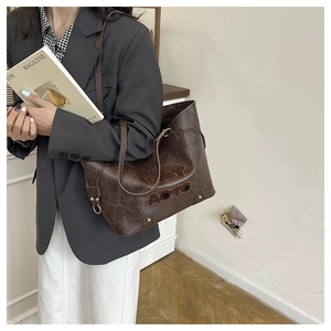 Detail of dark brown faux leather tote with plush letter patch shown with lifestyle styling