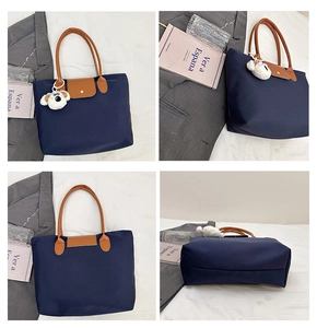 Detail view of large navy nylon tote with leather handles and white plush dog charm