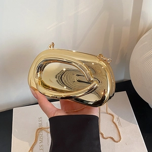 Detail shot of a sleek gold mirror-finish oval clutch bag with elegant metal chain strap