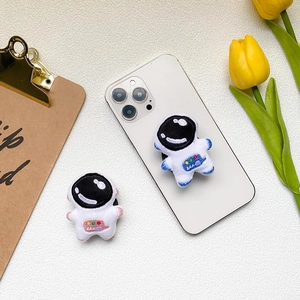 Cute plush astronaut phone pop socket grips in pink and blue on white smartphone