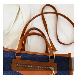Detalle de bolso tote de mezclilla con asas de cuero y herrajes de metal dorado