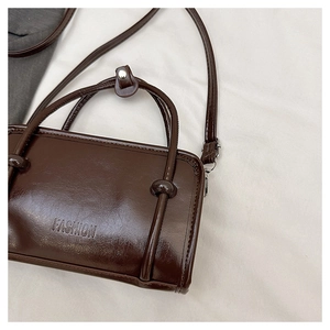 Detail of glossy brown leather bag showing Fashion debossing and knot handle design