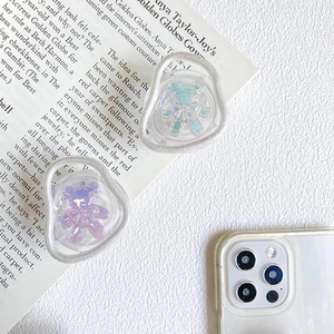 Detail of gradient bear phone grip holder on magazine with wavy transparent base