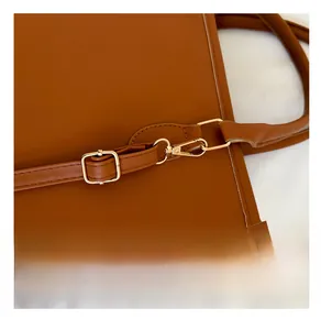 Detalle de la hebilla de metal dorado y las costuras en el bolso tote de cuero marrón