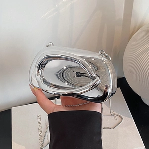 Detail of silver mirror clutch bag featuring sculptural handle and metal ball chain strap
