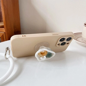 Beige iPhone case with floral resin griptok and white silicone wrist strap on white desk