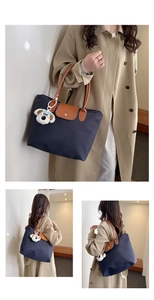 Detail of navy nylon tote with brown leather handles and a cute plush dog pendant