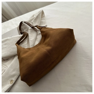 Detailed macro view of dark brown suede hobo bag texture with silver metal buckle