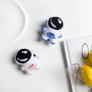 Detail of plush astronaut phone grips featuring blue and pink embroidery on white background