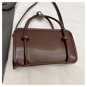 Close-up of chocolate brown glossy leather bag with FASHION logo and ball charms