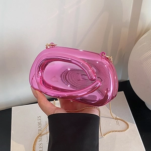 Detailed view of pink metallic clutch bag with oval hollow handle and gold chain strap