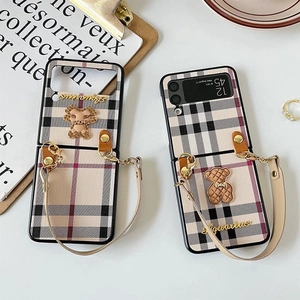 Detail of Galaxy Z Flip case with classic plaid texture, 3D bear, and leather handle strap