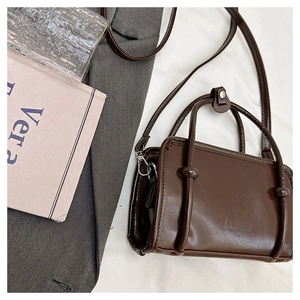 Detail of dark brown mini leather handbag featuring the FASHION embossed logo and top handle