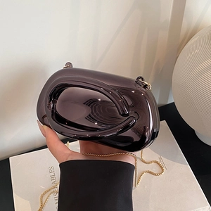 Detail of a dark gray mirror finish clutch bag with gold chain strap and sleek curves
