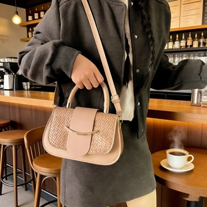 Beige crossbody bag with woven texture detail on wooden cafe bar counter setup