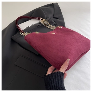 Macro shot of burgundy corduroy tote bag featuring gold chain strap and metal detail