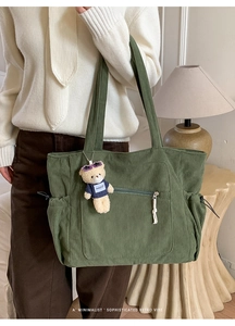 Detailed texture of green corduroy tote bag with front zipper pocket and bear charm
