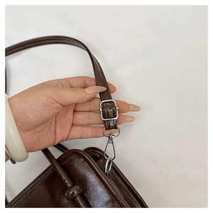 Detailed close-up of adjustable strap with silver-tone buckle on dark brown leather bag