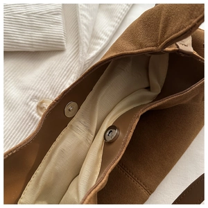 Detail view of brown suede tote bag featuring internal fabric lining and magnetic closure