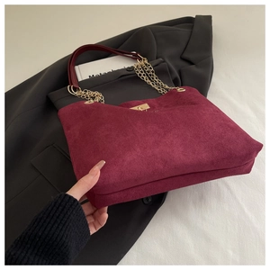 Macro detail of wine red suede tote bag with metal chain strap and luxury texture