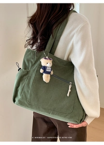 Detail of dark green corduroy tote bag featuring front zip pocket and cute bear charm