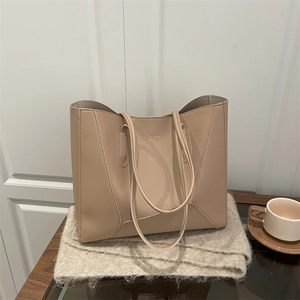 Grand cabas minimaliste en cuir beige avec lettrage doré sur une table dans un décor cosy
