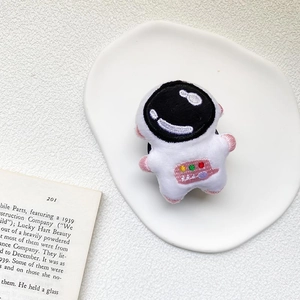 Detail of cute plush astronaut phone grip with soft embroidery on a white display tray