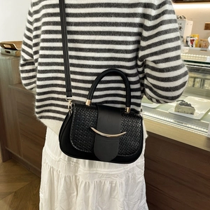 Detail of black faux crocodile texture handbag with crescent moon gold buckle shown on model