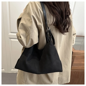 Detail of a black suede-like shoulder bag with long straps on a model back view