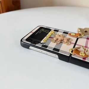 Detail of plaid fabric phone case with golden bear charm and wrist strap for Z Flip