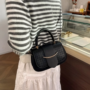 Detail of crocodile embossed leather bag with gold crescent buckle in casual cafe setting